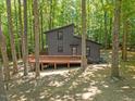 Rear exterior view featuring a wooden deck of a charming home nestled among mature trees at 3218 Seven Springs Rd, Hillsborough, NC 27278