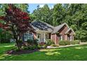 Red brick home featuring a lush, green lawn, a vibrant red tree, and a welcoming covered porch at 745 Oaks Lane Rd, Timberlake, NC 27583