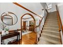 Welcoming foyer featuring hardwood floors, an elegant staircase, and archway to the dining room at 1030 W Sterlington Pl, Apex, NC 27502