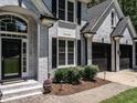 Close-up of a gray brick home entrance with black shutters and a two-car garage at 104 Warley Cir, Cary, NC 27513