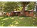 Cozy brick ranch-style home with a lush green lawn and mature trees providing shade and curb appeal at 1120 E Oak Dr, Durham, NC 27712