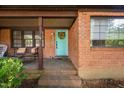 Welcoming brick front porch featuring a quaint seating area and a pop of color with a turquoise door at 1120 E Oak Dr, Durham, NC 27712