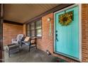 Inviting covered porch with seating area, brick facade, and a cheerful turquoise front door with wreath at 1120 E Oak Dr, Durham, NC 27712