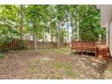 Spacious backyard with mature trees, wooden privacy fence, and a raised deck with a built-in bench at 205 Mint Hill Dr, Cary, NC 27519