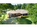 Aerial view of a brick home with metal roof, covered parking, and mature trees at 2081 Stone Street Ext, Mebane, NC 27302