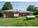 Exterior view of brick home showcasing propane tanks and metal roof at 2081 Stone Street Ext, Mebane, NC 27302