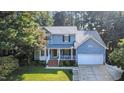 Charming two-story home with a welcoming front porch and a well-manicured lawn surrounded by mature trees at 302 Caraway Ln, Cary, NC 27519
