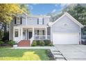 Beautiful two-story home with a charming front porch, brick stairs, and a two-car garage, surrounded by green lawn at 302 Caraway Ln, Cary, NC 27519