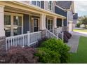 Charming covered front porch with classic white railings, brick details, and lush landscaping at 3624 Regent Pines Dr, New Hill, NC 27562