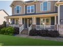 Inviting front porch featuring brick accents, white railings, beautiful landscaping, and a charming entrance at 3624 Regent Pines Dr, New Hill, NC 27562
