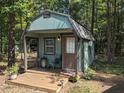 Cozy green shed with a porch, single door, and window, surrounded by lush greenery at 4008 Old Nc 86, Hillsborough, NC 27278
