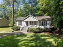 Charming single-story home with a cozy front porch and lush green lawn, surrounded by mature trees at 472 Shawnee Dr, Louisburg, NC 27549