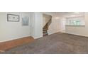 Open-concept living room featuring carpet, stairs, white walls, and hardwood flooring at 4802 Parkville Dr, Raleigh, NC 27604