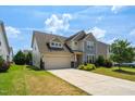 Two story home featuring a two-car garage, well-maintained lawn, and stone accents at the base at 517 Eagles Way, Mebane, NC 27302