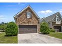 Beautiful home showcasing a stone facade, well-maintained lawn, and attached garages at 5216 Marcella Ct, Durham, NC 27707