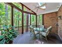 Screened-in back patio with glass table, cushioned chairs, ceiling fan, and wooded views at 81106 Alexander, Chapel Hill, NC 27517