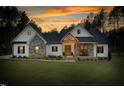 Charming home featuring stone accents, a welcoming front porch and bench, against a sunset at 1050 Southern High School Rd, Burlington, NC 27215