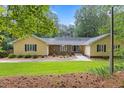 Inviting yellow home featuring a stone facade, well-manicured lawn and mature landscaping at 106 Autumn Cir, Cary, NC 27518