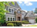 Attractive home with stone accents, gray siding, and a well-maintained front yard with mature landscaping at 108 Holly Glen Ct, Holly Springs, NC 27540