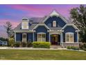 Charming two-story home featuring a blue exterior, stone accents, a well-manicured lawn, and solar panels at 119 Florentino Ct, Clayton, NC 27527