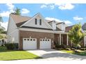 Brick home featuring a two-car garage, landscaped front yard, and a covered porch with white columns at 1217 Clandon Square Rd, Hillsborough, NC 27278