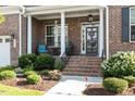 Inviting front porch with white pillars, decorative wreath on the front door, and lush landscaping at 1217 Clandon Square Rd, Hillsborough, NC 27278