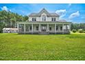 Spacious farmhouse with wrap-around porch, set on a sprawling green lawn under a bright sky at 1230 Sykes Rd, Spring Hope, NC 27882