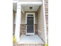Close-up of the front door with stone detailing, a covered porch, and neutral siding at 1402 Southpoint Trl, Durham, NC 27713