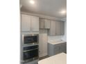 Kitchen features gray cabinets, stainless steel appliances including built-in microwave and oven, and white countertops at 1524 Chirping Bird Ct, Cary, NC 27519