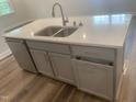 Kitchen island with stainless steel sink, white countertop, gray cabinets and drawers, and stainless steel dishwasher at 1524 Chirping Bird Ct, Cary, NC 27519