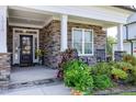 Inviting front porch with stone accents, rocking chairs, and lush landscaping at 1918 Morning Fog Dr, Fuquay Varina, NC 27526