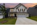 Charming two-story home with stone accents, a well-manicured lawn, and a two-car garage during sunset at 27 Silver Moon Ln, Clayton, NC 27527