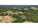 Wide aerial shot showcases farmland with a pond, fields, and multiple structures surrounded by trees at 2856 Gwyn Rd, Elon, NC 27244