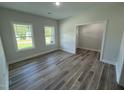 Bright bedroom with gray wood-look floors, two windows, and a doorway leading to another room at 290 Busterfield Ct, Benson, NC 27504