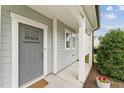 Elegant front entrance with a stylish gray door, white trim, and a cozy welcome mat at 3194 Retama Run, New Hill, NC 27562