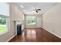 Bright living room with a cozy fireplace, hardwood floors, large windows, and a ceiling fan at 3417 Cardinal Lake Dr, Durham, NC 27704