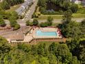 Aerial view of a sparkling community pool with lounge chairs and umbrellas surrounded by lush trees at 3417 Cardinal Lake Dr, Durham, NC 27704