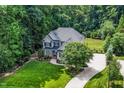 Aerial view of home with a long driveway and lush green lawn surrounded by mature trees at 3748 Westbury Lake Dr, Raleigh, NC 27603