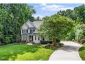 Beautiful home with a curved driveway, lush lawn, mature trees, and manicured landscaping at 3748 Westbury Lake Dr, Raleigh, NC 27603