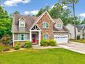 Charming home with stone accents, a bright red front door, attached two-car garage and mature trees at 39 Westover Ct, Sanford, NC 27332