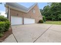 Side angle view of a home's brick exterior and a spacious three-car garage with white doors at 402 Bridewell Ct, Cary, NC 27518