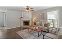 Cozy living room featuring a fireplace, neutral colored furniture, ceiling fan and decorative rug on a wood floor at 404 Ascott Way, Durham, NC 27713