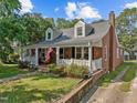 A charming brick home featuring dormer windows, an American flag and a cozy front porch at 412 Coggeshall St, Oxford, NC 27565