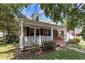 Inviting red brick house featuring a cozy front porch with white railing and lush landscaping at 412 Coggeshall St, Oxford, NC 27565
