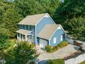 Aerial view of blue two story home showcasing pristine landscaping, garage, and spacious driveway at 4151 Deep Wood Cir, Durham, NC 27707
