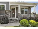 Close-up of front door with stone accents, porch, and landscaped bushes at 465 Gianna Dr, Clayton, NC 27527