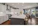 Sun-filled kitchen boasts an island with seating, granite countertops, white cabinets, and a view to the backyard at 521 Morning Oaks Dr, Holly Springs, NC 27540
