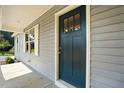 Close-up of a dark teal front door with windows and gray siding at 5500 Lake Wendell Rd, Zebulon, NC 27597
