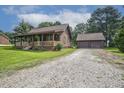 Log home with long front porch and an oversized detached garage on a gravel driveway at 5593 Leon Rd, Nashville, NC 27856