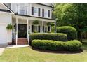 Inviting front porch with manicured greenery, hanging plants, and classic black shutters at 5833 Dahlberg Dr, Raleigh, NC 27603